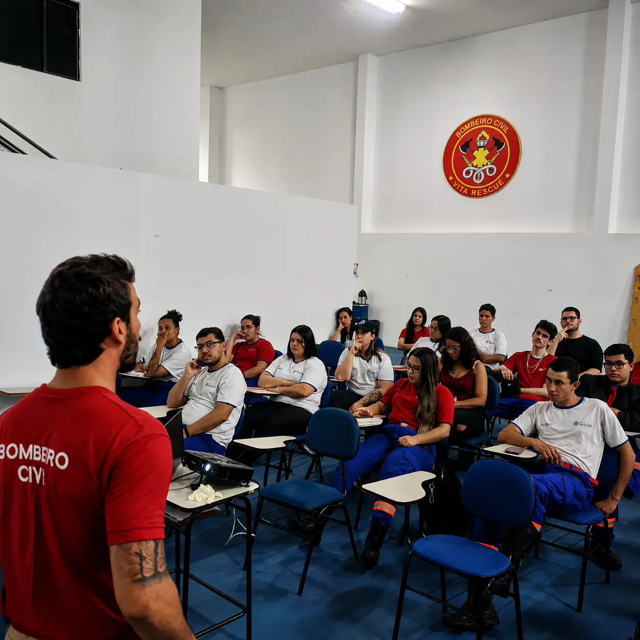 Instrutor Bombeiro Civil da Integra SST conduzindo treinamento teórico em sala cheia de alunos uniformizados