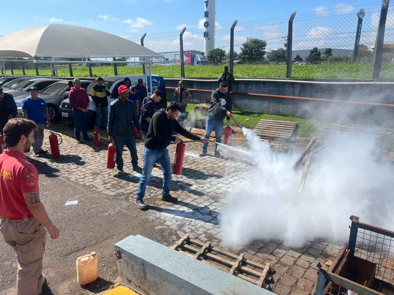 Participantes em treinamento empresarial de combate a incêndio com extintores